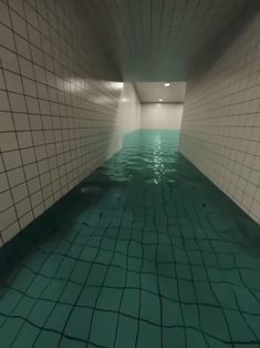 an underground swimming pool with tiled walls and green water in the center, surrounded by white tiles