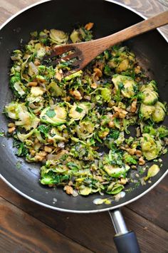 a skillet filled with cooked vegetables on top of a wooden table next to a spatula