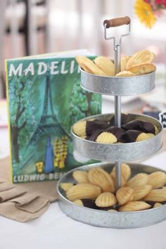 three tiered trays filled with cookies on top of a table next to a book