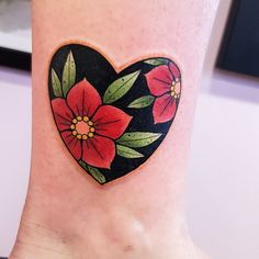 a heart shaped tattoo with flowers painted on it