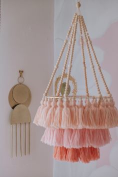 a pink and orange hanging mobile next to a white wall with a clock on it