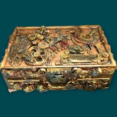 an ornately decorated wooden box with many different items on it's lid and sides