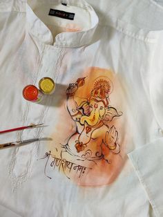 a shirt with an image of ganesh on it next to some paintbrushes