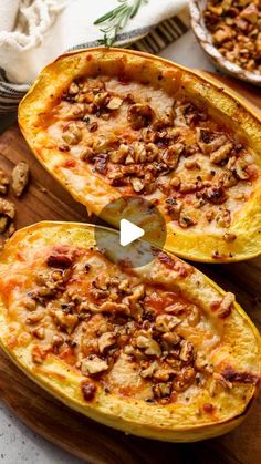 two stuffed acorns on a cutting board, one with nuts and the other topped with cheese