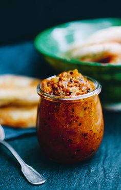 a small glass jar filled with food next to some breadsticks on a table