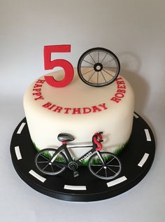 a birthday cake with a bicycle on the front and number five on the back, sitting on top of a black plate