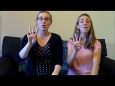 two young women sitting on a couch making the peace sign with their hands in front of them