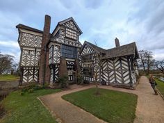 an old house with black and white paint on it's walls, in the middle of a grassy area