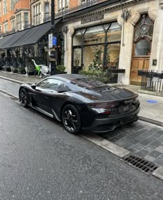 a black sports car is parked on the side of the street in front of a building