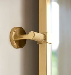 a close up of a door handle on a white and gold door with sunlight coming through the window