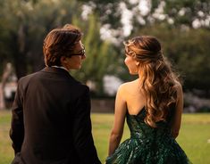 a man and woman in formal wear standing next to each other looking at each other