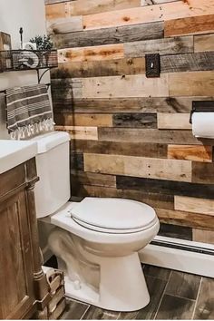 Modern bathroom with wooden accent wall and rustic decor, including a white toilet and mounted toilet paper holder. Pallet Wall Ideas, Flooring On Walls, Diy Wooden Wall, Wood Wall Bathroom, Wood Plank Walls, Dream Farmhouse