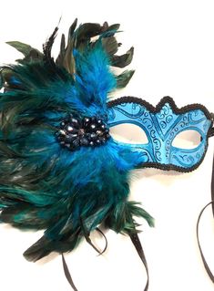 Masks Turquoise mask- Halloween- feather Masquerade Mask- Mardi Gras- Holiday Mask- Masked ball -Masquerade party Hello,  This feather mask is a so pretty and is made with turquoise coque feathers are about to 8", They fan out and are placed on a beautiful matching sparkle mask.       The tie is a matching sparkle velvet that is 3/8" wide.  The black glass piece is 3".  Also great for any party or performance! Feathers...available  Turquoise Hot pink White Red -------------------------------------------------- The mask is made with a matching black sparkle tie.  Cardboard molded over plastic mask/ makes it durable and then its painted. Custom colors available. ---------------------------------------- To return to my shop: https://www.etsy.com/shop/doramarra?ref=si_shop -------------------- Feather Masks For Carnival Costume Party, Feathered Masks For Carnival Costume Party, Blue Venetian Masquerade Mask For Party, Blue Carnival Costume Accessories, Feathered Masks For Masquerade Carnival, Feathered Masquerade Mask For Mardi Gras, Feathered Masquerade Mask For Carnival Party, Mardi Gras Feathered Masquerade Mask For Party, Blue Venetian Masks For Masquerade