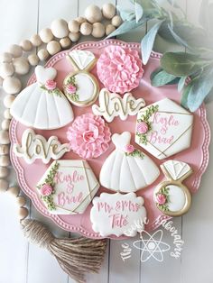 decorated cookies are arranged on a pink platter with greenery and beads around it