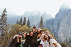 a group of young people standing next to each other in front of mountains and trees