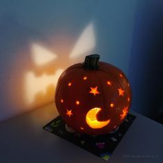 a carved pumpkin sitting on top of a table next to a shadow cast by a light