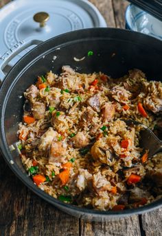 a pan filled with rice and meat on top of a wooden table