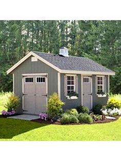 a small shed in the middle of a yard with flowers and shrubs around it,