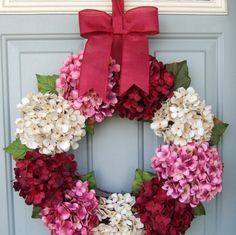 a wreath with pink and white flowers is hanging on a door