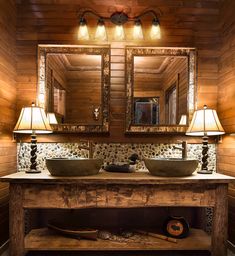 a rustic bathroom with two sinks and large mirrors on the wall, along with lamps