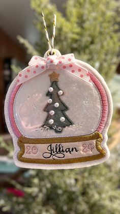 a glass ornament with a christmas tree on it's side hanging from a string