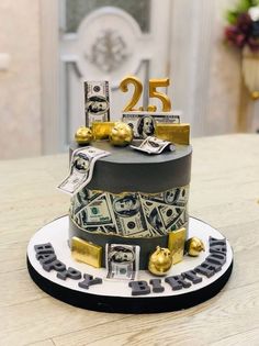 a cake with money on top and the number twenty five in gold is sitting on a table