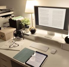 a desk with a computer monitor, keyboard and mouse on it next to a lamp