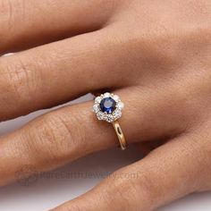 a woman's hand with a blue and white diamond ring on her left hand