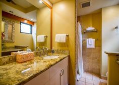 a bathroom with marble counter tops and yellow walls