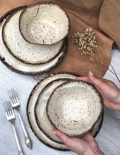 a person is holding three plates with silverware next to each other on a table