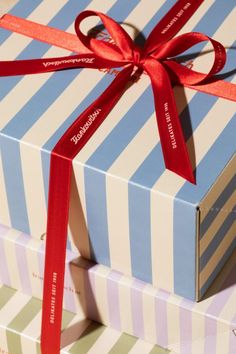 two boxes wrapped in blue and white striped paper with a red ribbon tied around them