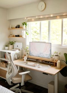 a desk with a computer on it in front of a window and some potted plants