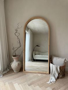 a large mirror sitting on top of a wooden floor next to a vase and pillow