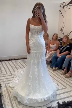 a woman in a white wedding dress is taking a selfie with her cell phone