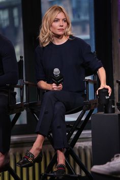 a woman sitting in a chair holding a microphone and talking to someone on the other side