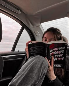 a woman sitting in the back seat of a car reading a book