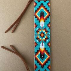 a colorful beaded tie sitting on top of a table next to two brown sticks