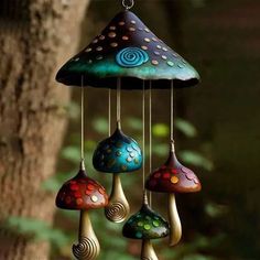 a wind chime hanging from a tree in the forest with colorful mushrooms on it