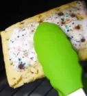 a green spatula sitting on top of a piece of food