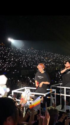 two men standing on top of a white railing in front of an audience at a concert