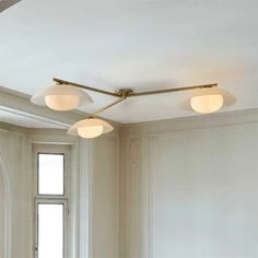 three lights are hanging from the ceiling in a room with white walls and wood floors