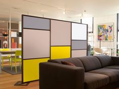 a living room filled with furniture and lots of colorful panels on the wall next to a window