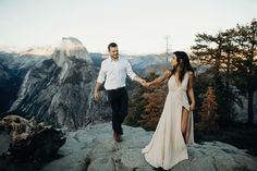 a man and woman holding hands on top of a mountain