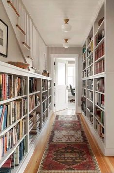 a long hallway with many bookshelves and rug on the floor