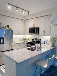 a modern kitchen with stainless steel appliances and granite counter tops, along with white cabinets