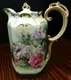 a vase with flowers painted on it sitting on a table