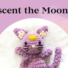 a purple crocheted cat sitting on top of a white circle with the words crescent the moon