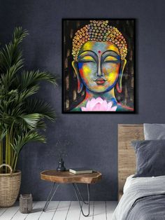 a buddha painting hanging on the wall above a bed with a plant in front of it