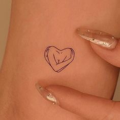 a woman's stomach with a small heart tattoo on her left side ribcage