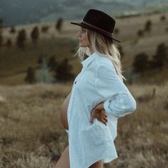 a woman in a white shirt and black hat is posing for the camera with her hands on her hips